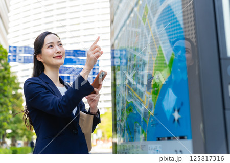 地図とスマホを見て場所を確認する女性ビジネスパーソン 125817316