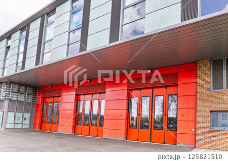 Bright red fire station doors on modern brick building with glass windows 125821510