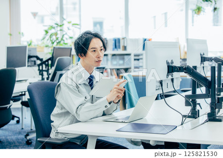 会社で働く作業着の若い男性 会社で働く作業着の若い男性 125821530