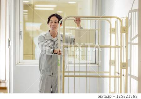 コンテナを運ぶ作業着を着た男性 125821565