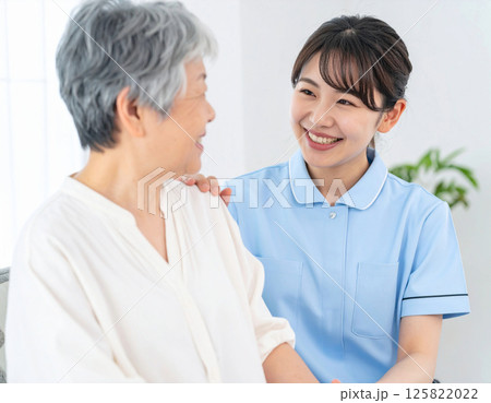 シニアに微笑む女性介護士 125822022