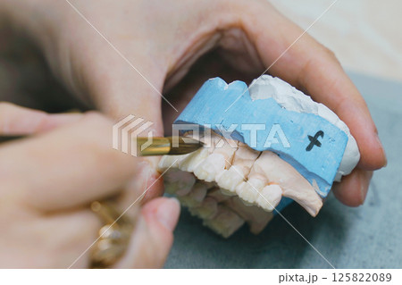 Dental Technician Carefully Brushes Denture Mold During Manufacturing Dental Technician Carefully Brushes Denture Mold During Manufacturing 125822089