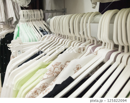 Neatly arranged clothing on hangers in a retail store during daytime 125822094