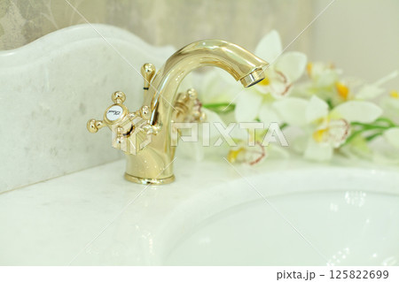 Marble and gold. Golden faucet on stone surface in luxurious bathroom, interior detail 125822699