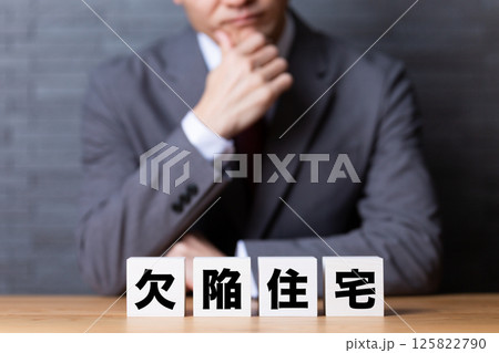 欠陥住宅のブロックとスーツを着て悩むミドル男性ビジネスマン 欠陥住宅のブロックとスーツを着て悩むミドル男性ビジネスマン 125822790