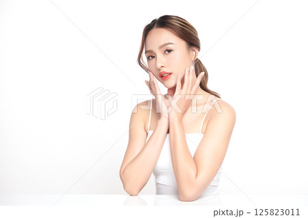 A beautiful young Asian woman with clean, fresh skin against a white background. Skincare, facial treatment, cosmetology, beauty, and spa. An elegant portrait of an Asian woman. 125823011