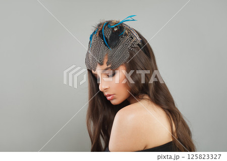 Stylish healthy woman with makeup, long brown curly hair and hair deco feathers accessories 125823327