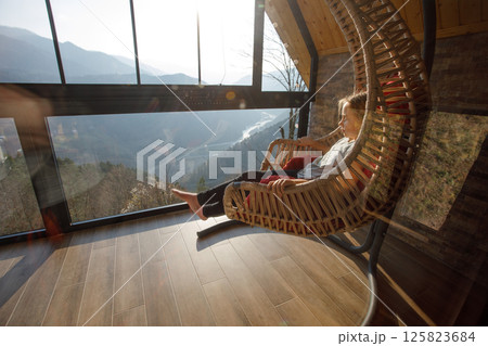 Child girl sitting in the hammock and looking on the mountains in Variaki, Georgia 125823684