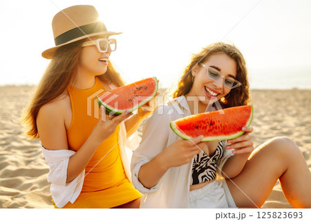 Smiling two women eating watermelon on beach. Happy summer time. People, lifestyle, travel 125823693