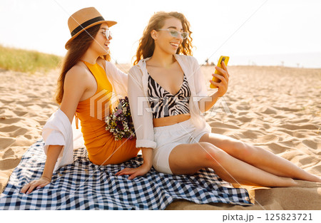 Two pretty friends women making selfie on beach, light and bright summer colors. Friends together Two pretty friends women making selfie on beach, light and bright summer colors. Friends together 125823721