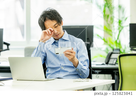 オフィスでスマホゲームをするビジネスマン オフィスでスマホゲームをするビジネスマン 125823841