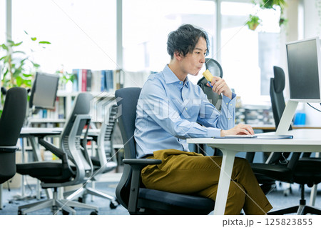 オフィスでプロテインバーを食べる男性 オフィスでプロテインバーを食べる男性 125823855