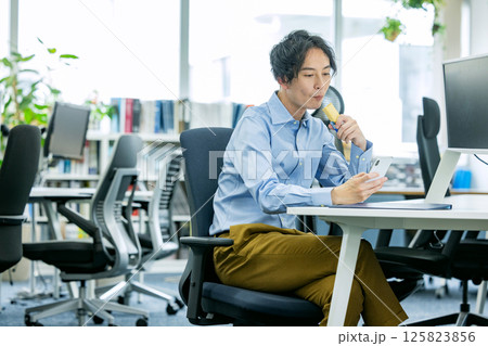 オフィスでプロテインバーを食べる男性 オフィスでプロテインバーを食べる男性 125823856