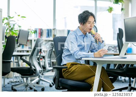 オフィスでプロテインバーを食べる男性 125823857