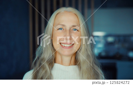 Portrait of beautiful happy smiling mature woman looking at camera in room at home 125824272