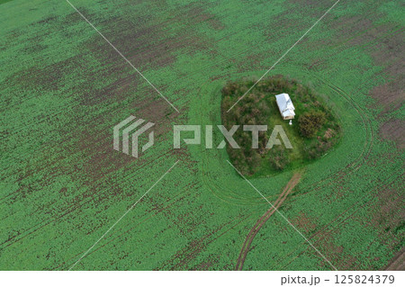 Aerial view of small white chapel in the middle of agricultural field 125824379