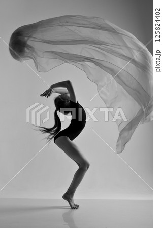 A girl in a swimsuit and a dress shows beautiful athletic elements on a white background. Ballet, rhythmic gymnastics, fabric, aesthetics, grace. High quality photo 125824402