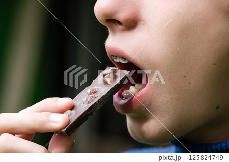 Child eating a piece of chocolate with nuts. 125824749