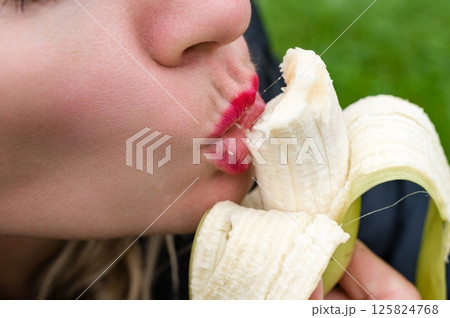 Woman with red lipstick eating a banana 125824768