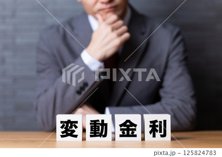 変動金利のブロックとスーツを着て悩むミドル男性ビジネスマン 変動金利のブロックとスーツを着て悩むミドル男性ビジネスマン 125824783