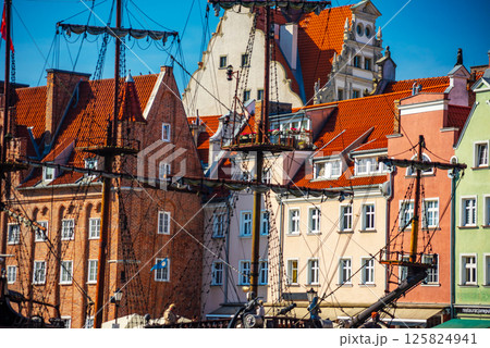 Scenic view of Gdansk's historic architecture, showcasing colorful, traditional buildings with red-tiled roofs. A tall ship mast enhances the city's rich maritime history charm 125824941
