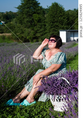 Woman in a lavender field, holding a basket of freshly picked lavender. Woman in a lavender field, holding a basket of freshly picked lavender. 125824995