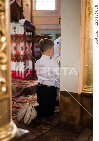 Young boy kneeling in prayer inside a church, seeking solace and spiritual guidance. Young boy kneeling in prayer inside a church, seeking solace and spiritual guidance. 125825018