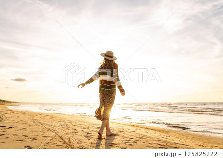 Carefree woman relaxing on coast at sunset. Windy autumn days. The concept of relaxation Carefree woman relaxing on coast at sunset. Windy autumn days. The concept of relaxation 125825222
