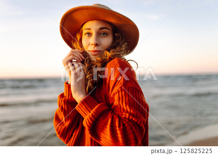 Portrait of a beautiful woman on the beach at sunset. Girl walks along the beach and enjoys weather Portrait of a beautiful woman on the beach at sunset. Girl walks along the beach and enjoys weather 125825225