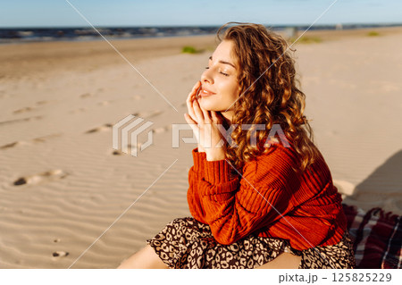 Portrait of curly woman on beach in cold sunny weather. Travel, weekend, relax and lifestyle concept 125825229