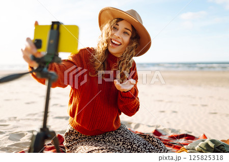 Happy woman using smartphone with stabilizer, live video in on sea beach. Live session blogging. 125825318