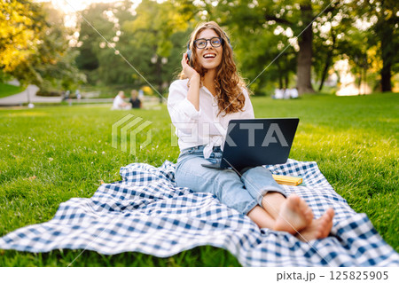 Young woman headphones sits listen to music use mobile cell phone. Concept for business, freelance. Young woman headphones sits listen to music use mobile cell phone. Concept for business, freelance. 125825905