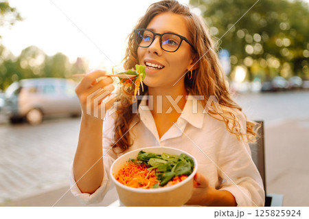Young tourist standing in the middle of the street, eating takeaway lunch while taking in the sights Young tourist standing in the middle of the street, eating takeaway lunch while taking in the sights 125825924