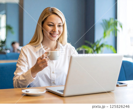 コーヒーを片手にテレワーク中のビジネスウーマン｜自宅やカフェでの在宅勤務シーンに最適 125826246
