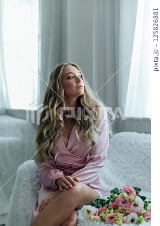 woman in summer pink dress with bouquet of spring flowers in white room 125826881