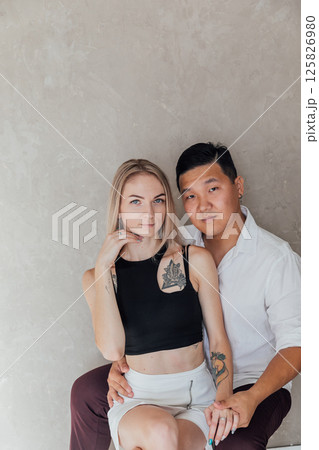 Asian man and blonde woman sitting and hugging together 125826980