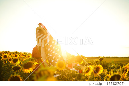 Beautiful girl in hat with the American flag in a sunflower field. 4th of July. Fourth of July. Independence Day. Beautiful girl in hat with the American flag in a sunflower field. 4th of July. Fourth of July. Independence Day. 125827074