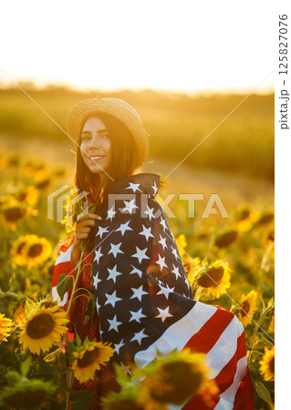 Beautiful girl in hat with the American flag in a sunflower field. 4th of July. Fourth of July. Independence Day. Beautiful girl in hat with the American flag in a sunflower field. 4th of July. Fourth of July. Independence Day. 125827076