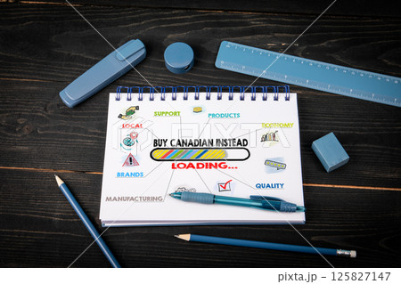 Buy Canadian Instead Loading. Notepad and blue stationery on a black wooden texture background 125827147