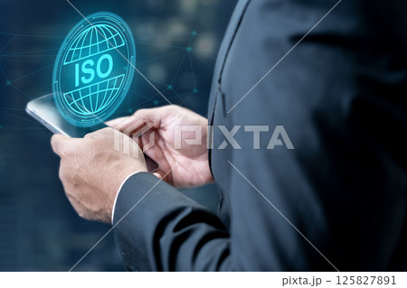 Businessman using a cellphone with an icon of a globe with ISO text. Technology innovation on a virtual screen. Concept of ISO certification, global standards, and quality assurance Businessman using a cellphone with an icon of a globe with ISO text. Technology innovation on a virtual screen. Concept of ISO certification, global standards, and quality assurance 125827891