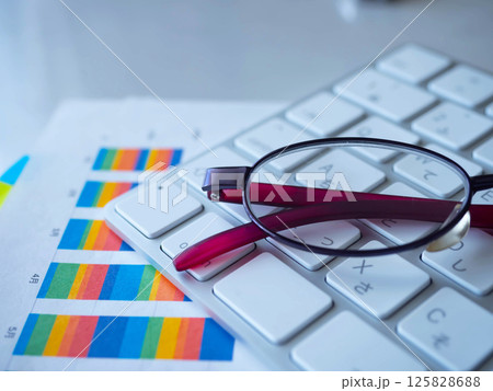 テーブルに置かれたグラフとキーボードとメガネ 125828688