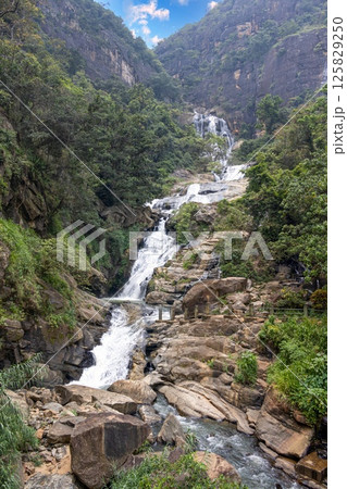 The tall Diyaluma waterfall cascades down a steep rocky slope in lush Sri Lankan highlands The tall Diyaluma waterfall cascades down a steep rocky slope in lush Sri Lankan highlands 125829250