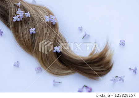 Female long hair with lilac flowers. Closeup, selective focus. 125829257