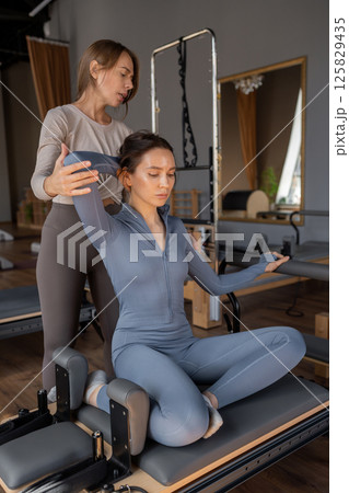 Woman doing mermaid exercise in a sunlite, modern pilates studio, embodying calm, focus, and strength. Woman doing mermaid exercise in a sunlite, modern pilates studio, embodying calm, focus, and strength. 125829435