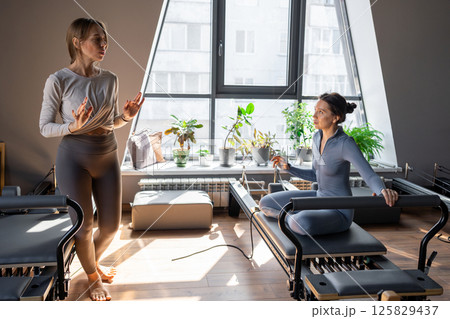 Woman doing mermaid exercise in a sunlite, modern pilates studio, embodying calm, focus, and strength. 125829437