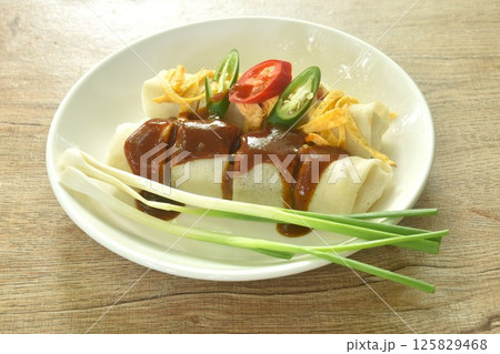 fresh Chinese spring roll made from flour wrapped tofu and pork with bean sprout dressing sweet red gravy sauce on plate    125829468