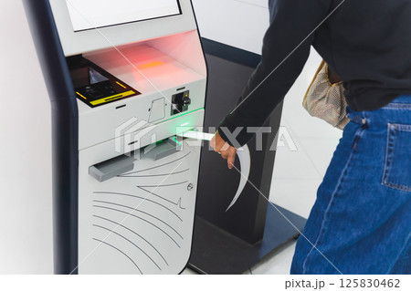 Woman traveler using self service check in machine at airport. Woman traveler using self service check in machine at airport. 125830462