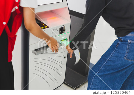 Woman traveler using self service check in machine at airport. Woman traveler using self service check in machine at airport. 125830464