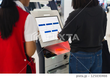 Woman at self service transfer area doing self check in at airport. Woman at self service transfer area doing self check in at airport. 125830466