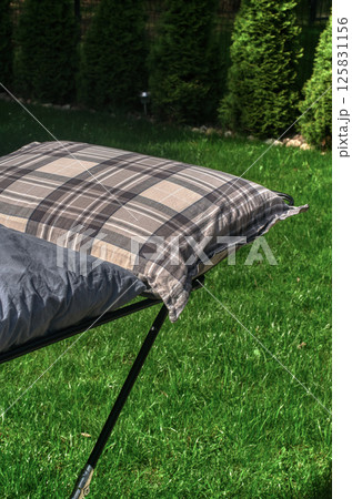 Plaid pillow airing on drying rack outside in backyard on a sunny green lawn. High quality photo 125831156